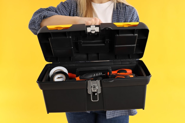 Concept of professions young woman holds tools on yellow background