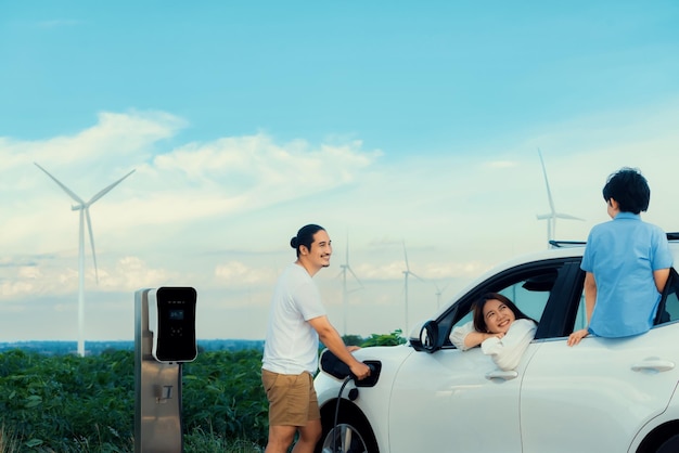 Concept of progressive happy family at wind farm with electric vehicle