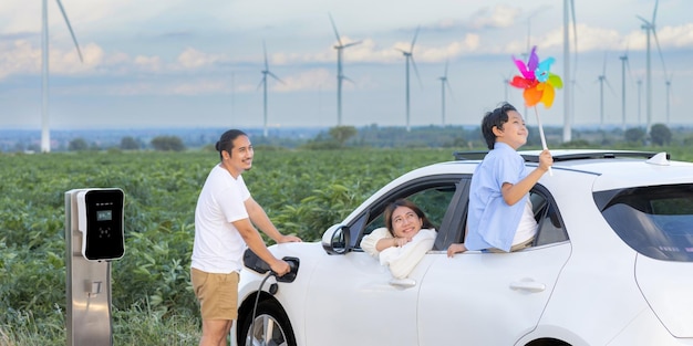 Concept of progressive happy family at wind farm with electric vehicle