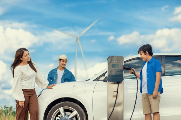 Concept of progressive happy family at wind farm with electric vehicle