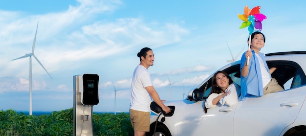 Concept of progressive happy family at wind turbine with electric vehicle