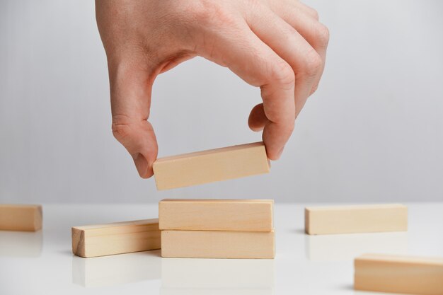 Concept of rebuilding a business after bankruptcy. Hand holds wooden blocks on a white space.