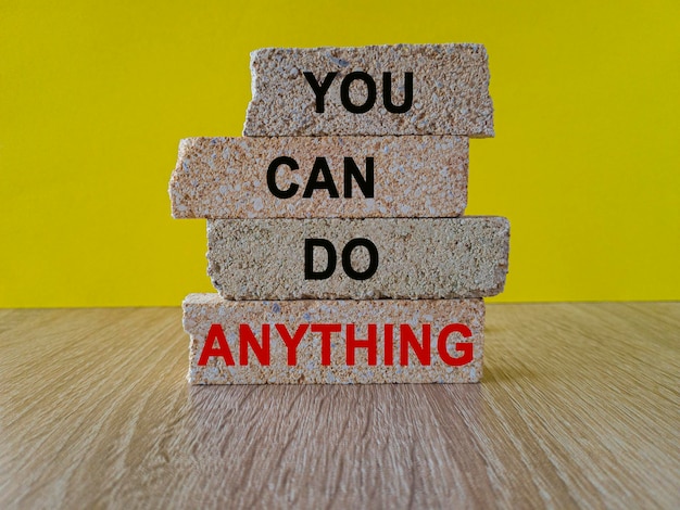 Concept red word You can do anything on brick block Beautiful wooden table yellow background