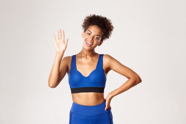 Concept of sport and workout. Attractive, healthy african-american female athlete, waving hand