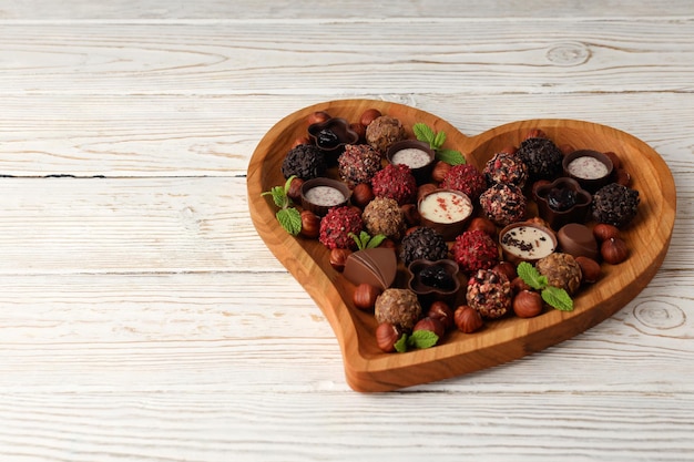 Concept of sweets with chocolate candies on white wooden background