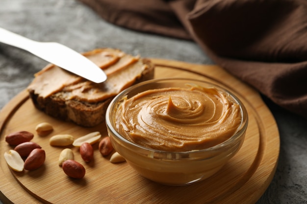 Concept of tasty breakfast with peanuts and peanut butter on gray table