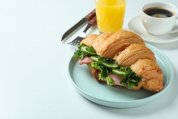 Concept of tasty eating with croissant sandwich on white