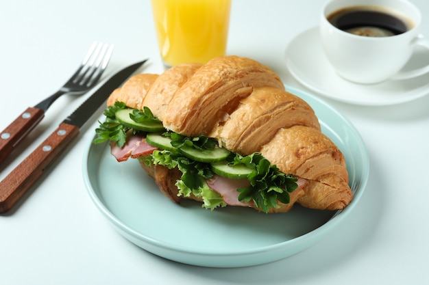 Concept of tasty eating with croissant sandwich on white