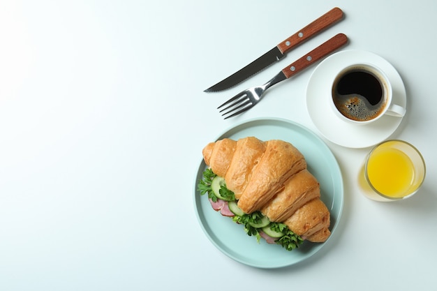 Concept of tasty eating with croissant sandwich on white