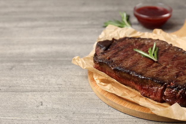 Concept of tasty food with beef steak on gray wooden background