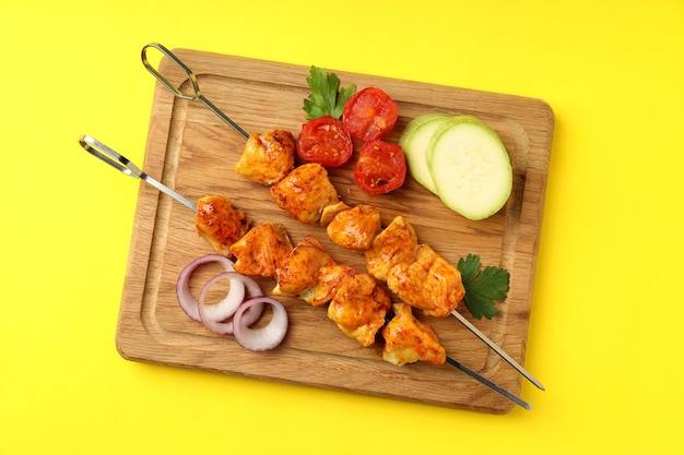 Concept of tasty food with chicken shashlik on yellow background