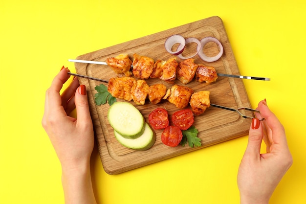 Concept of tasty food with chicken shashlik on yellow background