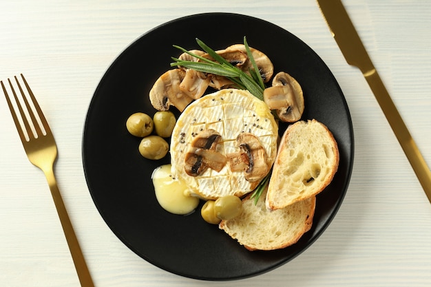 Concept of tasty food with grilled camembert on white wooden background.