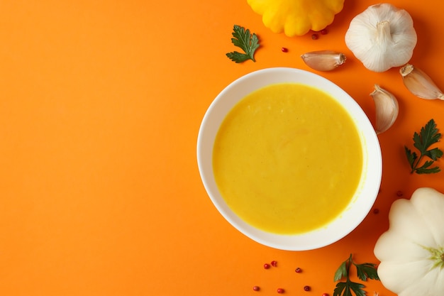 Concept of tasty food with pumpkin soup on orange background