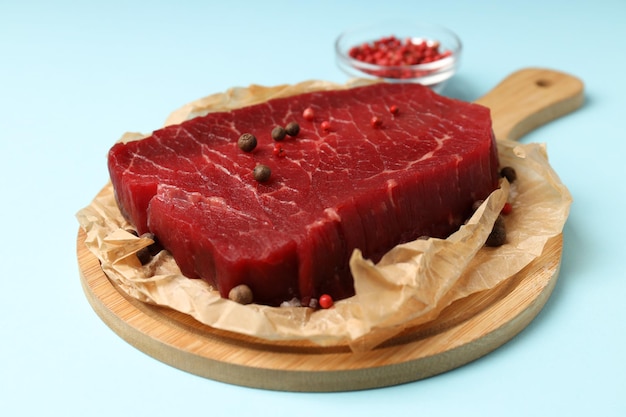 Concept of tasty food with raw beef steak on blue background