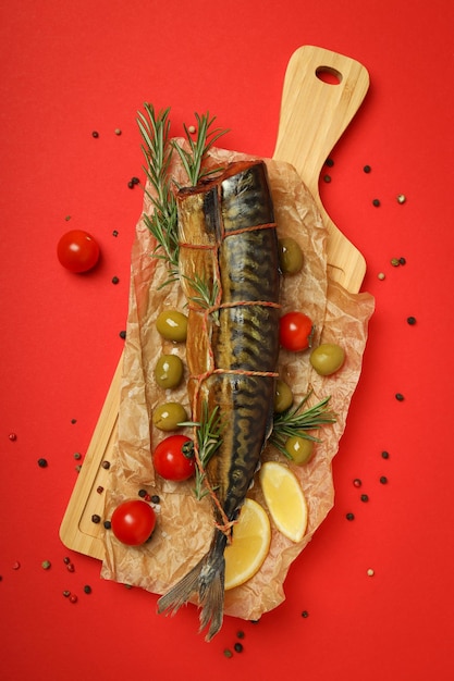 Concept of tasty food with smoked mackerel on red background