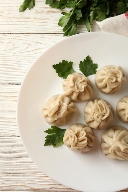 Concept of tasty lunch with plate of khinkali on white wooden table