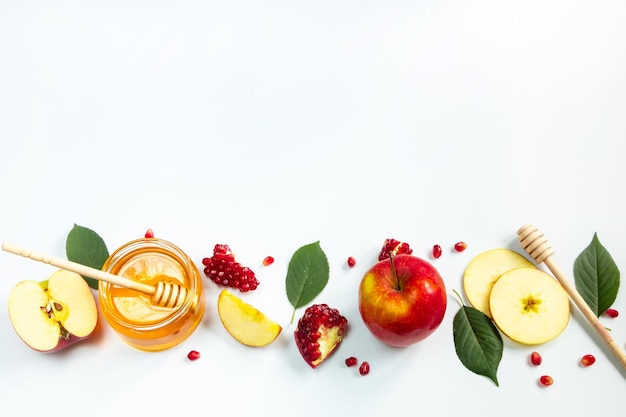 Concept of traditional Jewish holiday of Rosh Hashanah New Year Pomegranates honey and apples on white background Place for your text