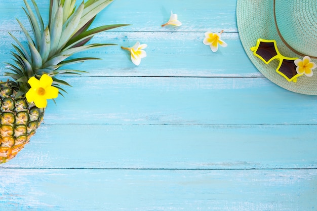 Concept of tropical fruit. Pineapple, flowers, sunglasses and straw hat 