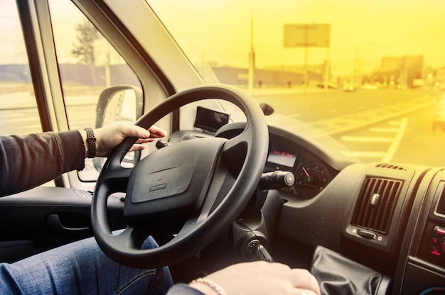 concept of a truck driver, driver's hands on the steering wheel on a sunny day in summer.