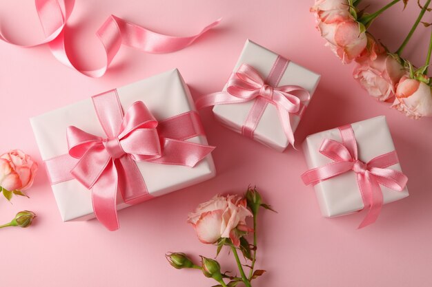 Concept of Valentine's day with gift boxes and roses on pink background