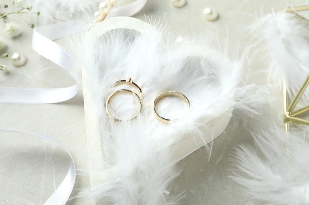 Concept of wedding accessories with wedding rings on white textured background