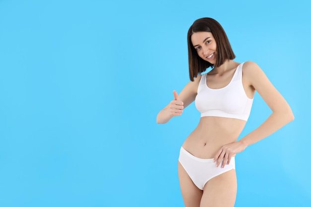 Concept of weight loss with slim young woman on blue background