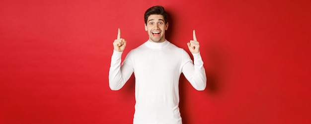 Concept of winter holidays goodlooking young man with bristle wearing white sweater showing christma