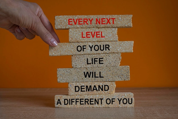 Concept words Every next level of your life will demand a different you Red words on brick blocks