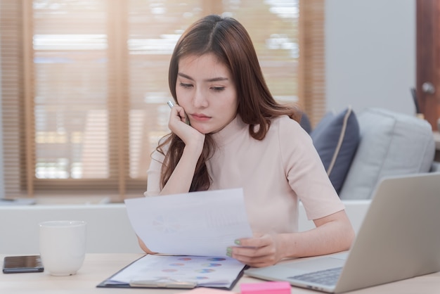 The concept of working from home, a beautiful Asian woman is working with a face that shows stress and anxiety.