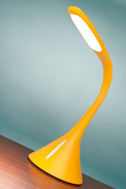 Photo concept of yellow led sensor desk lamp on a wooden table. 3d rendering