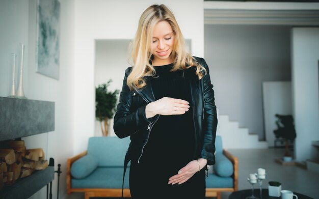 Concept - Young beautiful happy smiling pregnant caucasian blonde girl standing in white light living room