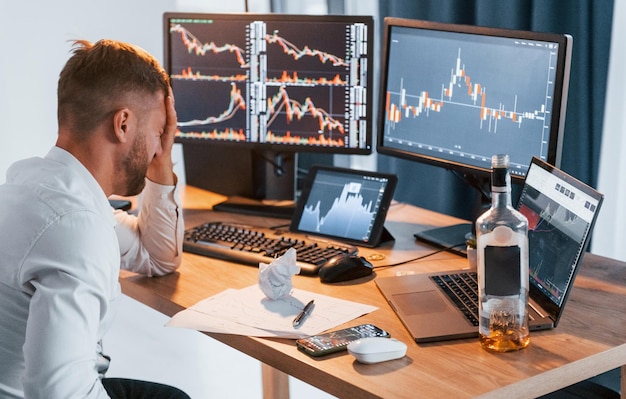 Conception of failure Young businessman in formal clothes is in office with multiple screens