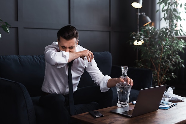 Concepts of alcoholism or problems in life. Upset businessman drinks vodka.