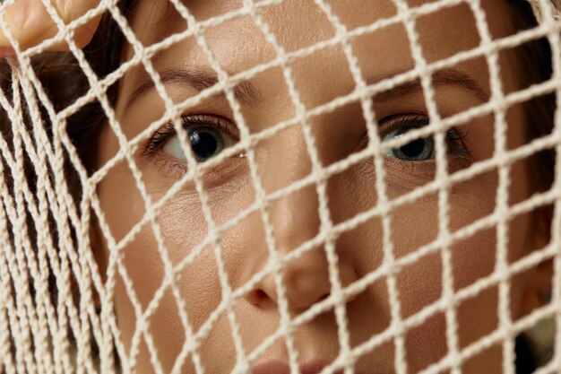 Conceptual Abstract Art Close up shot of curly beautiful female hold string bag near face seriously looks at camera posing isolated on olive green background Ecofriendly Natural products concept