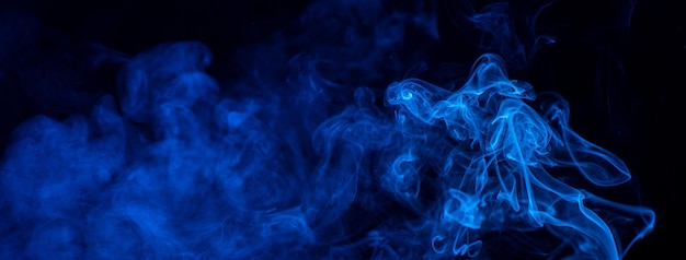 Conceptual image of blue color smoke isolated on dark black background Halloween design element concept