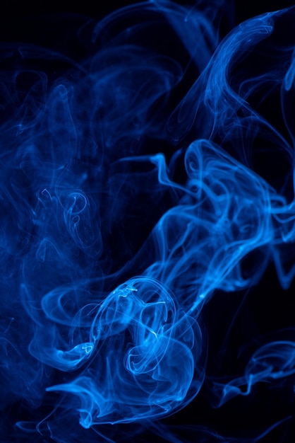 Conceptual image of blue color smoke isolated on dark black background Halloween design element concept