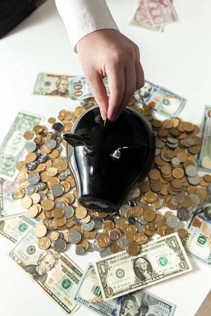 Conceptual photo of woman inserting coin in piggy bank