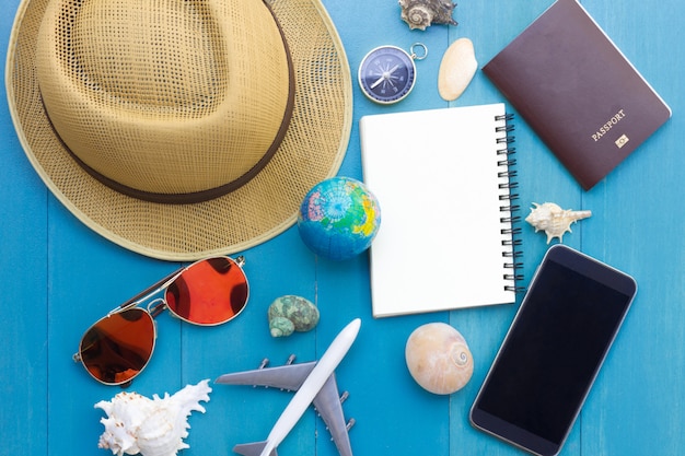 Conceptual tour planing image of travelling accessories on blue wooden background