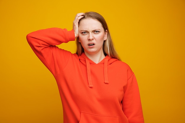 Concerned young blonde woman keeping hand on head 