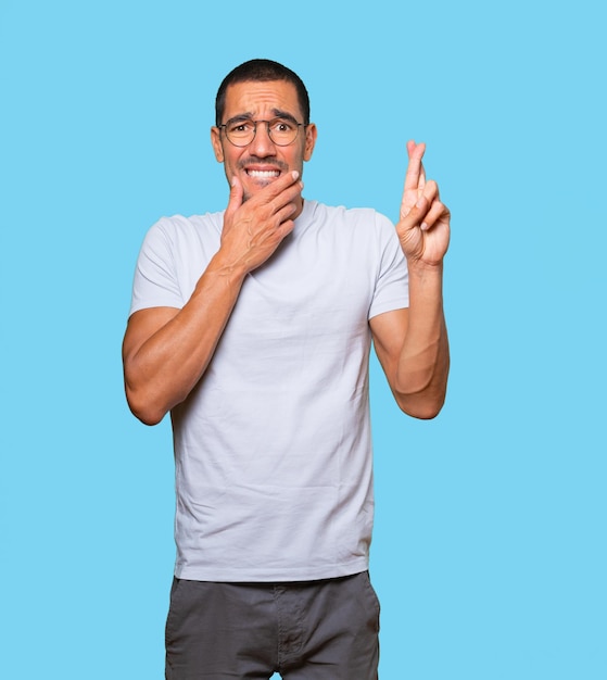 Concerned young man doing a crossed fingers gesture