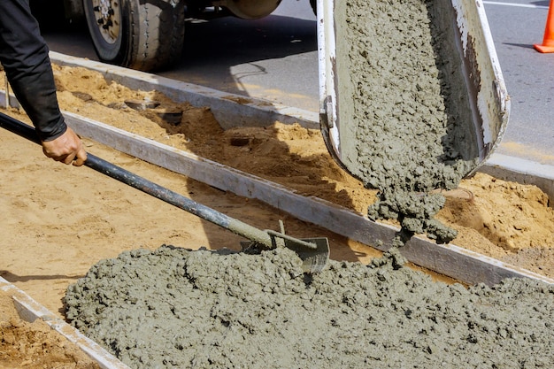 Concrete being poured from a truck into a concrete with sidewalk