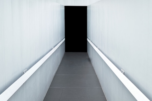 Concrete corridor with white wall and granite tile to black door