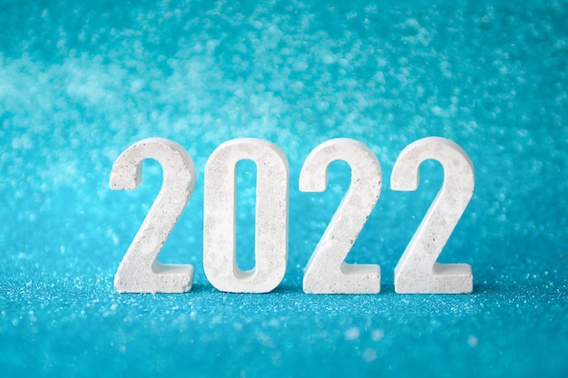 Concrete numbers 2022 on blue glittering background. copy space.