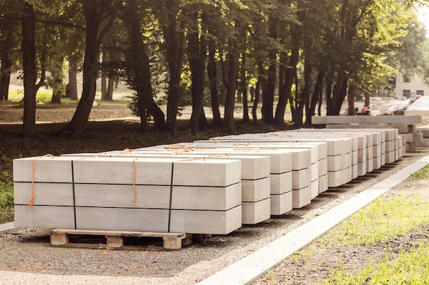 Concrete Slabs for Construction Pathway in Park. Concrete Blocks on Pallet. Curbstone Pallets.