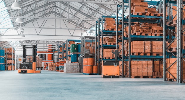 Concrete storage warehouse with pallets and shelves full of goods.