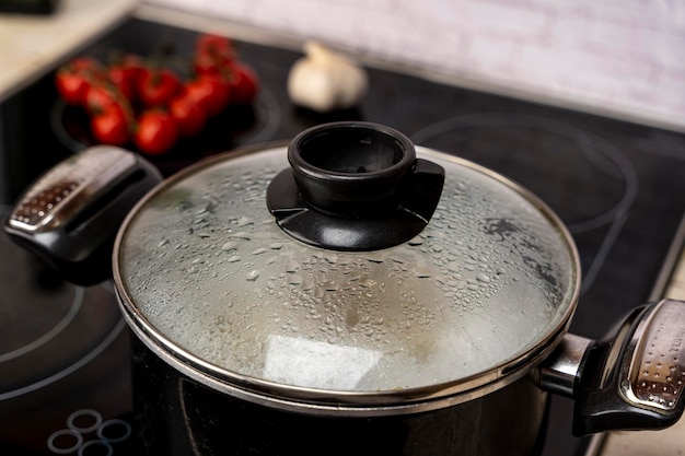 Condensation drops on the glass lid of the kitchen pot boiling