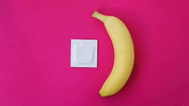 Condom and banana on pink background. Concept of sex