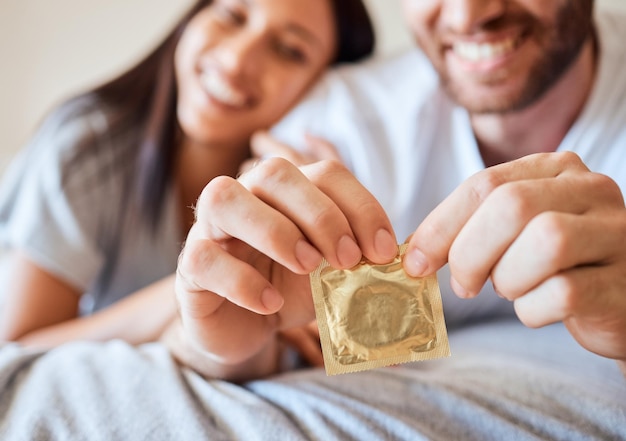 Condom couple and sex with the hands of a man opening protection for sexual intercourse in bed with a partner Happy love and safe with a woman and her boyfriend using contraceptive in the bedroom