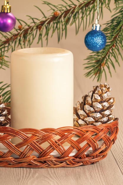 Cone candle and natural fir tree branches with Christmas ornament